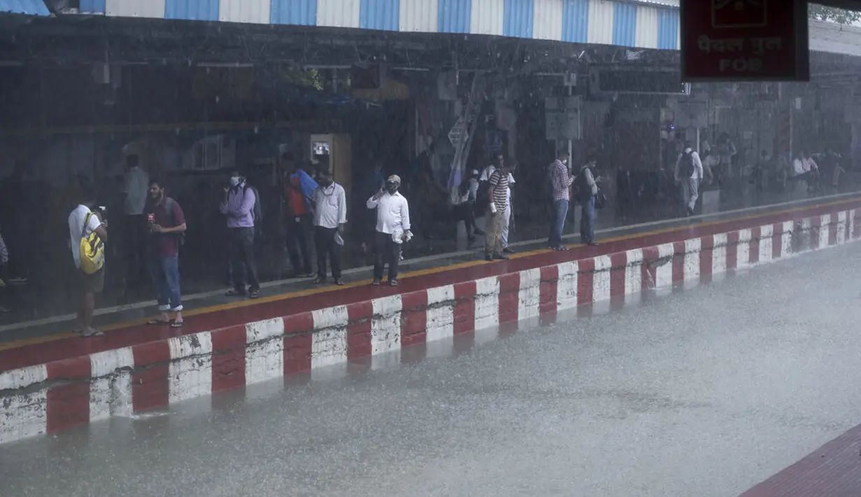 Orang-orang menunggu kereta sementara rel kereta api terendam banjir saat hujan lebat di Mumbai, India, Rabu (9/6/2021). Mumbai terendam banjir usai diguyur hujan lebat. (AP Photo/Rafiq Maqbool)