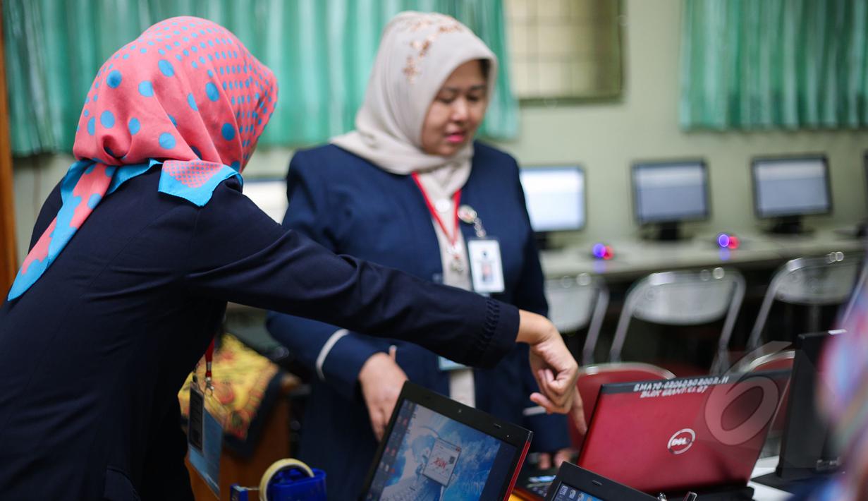 Sejumlah Guru mempersiapkan komputer untuk ujian nasional (UN) di SMA 70, Jakarta, Senin (13/4/2015). Sebanyak 585 dari 70 ribu sekolah menjadi percontohan menjalankan ujian nasional berbasis komputer di seluruh Indonesia.  (Liputan6.com/Faizal Fanani)