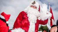 Santa Claus melambaikan tangan setibanya Kongres Dunia Sinterklas di Kopenhagen, Denmark, Senin (23/7). Kegiatan itu merupakan sarana dimana seluruh santa di dunia bisa bertemu dan melakukan aktivitas bersama. (Mads Claus Rasmussen/Scanpix via AP)