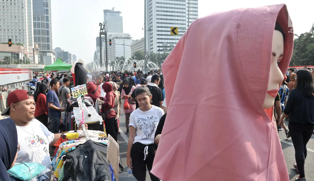 Warga melintasi lapak PKL saat car free day di MH Thamrin, Jakarta, Minggu (8/9/2019). Penutupan sebagian jalan akibat proyek revitalisasi trotoar membuat para PKL menggelar lapak hingga ke badan jalan sehingga menyebabkan aktivitas olahraga warga terhambat. (merdeka.com/Iqbal S. Nugroho)