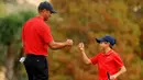 Maestro golf Tiger Woods tampak begitu dekat dengan anaknya yang bernama Charlie Axel Woods. (Mike Ehrmann/Getty Images/AFP)