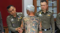 Petugas menunjukkan tato Mantan bos Yakuza asal Jepang, Shigeharu Shirai di sebuah kantor polisi saat konferensi pers di Lopburi, Thailand, Kamis, (11/1). Pria 72 tahun ini ditangkap setelah 14 tahun menjadi buronan. (AP Photo)