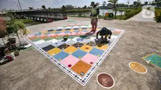 Petugas Sudin Pertamanan Jakarta Utara menyelesaikan pembuatan arena permainan tradisional di Taman Sungai Kendal, Cilincing, Kamis (27/5/2021). Pembuatan arena bermain seperti ular tangga ini untuk mengenalkan anak-anak tentang permainan tradisional sejak dini. (merdeka.com/Iqbal S Nugroho)