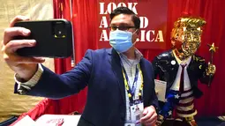 Seorang peserta berswafoto dengan patung emas Donald Trump pada Konferensi Politik Konservatif (CPAC) di Orlando, Florida, Jumat (26/2/2021). Patung setinggi lebih dari 6 kaki ciptaan seniman Tommy Zegansebagai tanggapan atas berbagai karya seni yang mengejek Trump. (AP Photo / John Raoux)