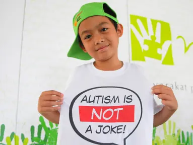 Seorang anak menunjukkan kaos bertuliskan "Autism is Not a Joke" saat acara Fun Walk 2015 di Balaikota DKI Jakarta, Minggu (29/3/2015). (Liputan6.com/Herman Zakharia)