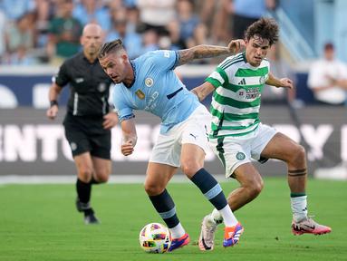 Gelandang Manchester City Kalvin Phillips berebut bola dengan gelandang Glasgow Celtic, Matt O'Riley dalam pertandingan uji coba di Stadion Kenan Momorial, Amerika Serikat, Rabu (24/7/2024) pagi WIB. (GRANT HALVERSON / GETTY IMAGES NORTH AMERICA / Getty Images via AFP)