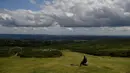 Seorang pejalan kaki memandang ke arah Torbay ketika mereka beristirahat di kaki Haytor Rocks di Taman Nasional Dartmoor, dekat Exeter, Inggris barat daya (12/8/2019). Dartmoor merupakan sebuah kawasan dataran tinggi di sebelah selatan Devon, Inggris. (AFP Photo/Ben Stansall)