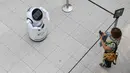 Seorang perempuan mengamati sebuah robot pintar yang menjelaskan tentang langkah pencegahan COVID-19 di sebuah pusat perbelanjaan di Frankfurt, Jerman, pada 12 September 2020. (Xinhua/Lu Yang)