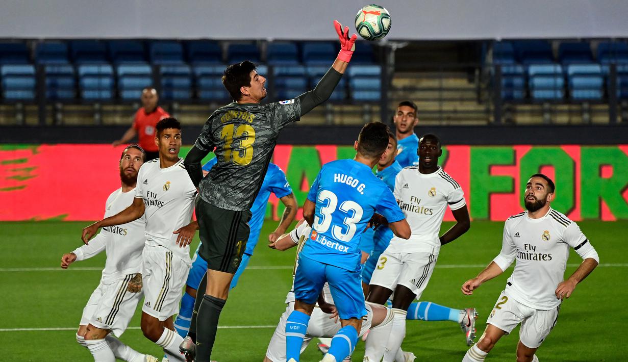 Kiper Real Madrid, Thibaut Courtois, berusaha menepis bola saat melawan Valencia pada laga lanjutan La Liga Spanyol pekan ke-29 di Stadion Alfredo, Stefano, Jumat  (19/6/2020) dini hari WIB. Real Madrid menang 3-0 atas Valencia. (AFP/Javier Soriano)