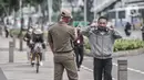 Petugas Satpol PP menegur pekerja yang salah menggunakan masker saat jam pulang kantor di kawasan Sudirman, Jakarta, Senin (14/9/2020). Pengurangan aktivitas pekerja di perkantoran menjadi fokus utama Pemprov DKI Jakarta dalam penerapan PSBB pada 14-27 September 2020. (merdeka.com/Iqbal S. Nugroho)