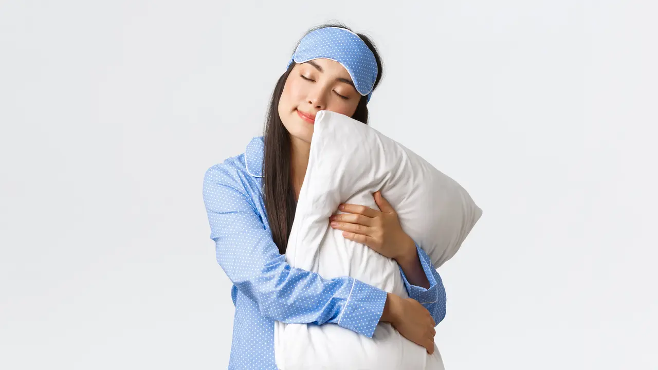 Seorang perempuan mengenakan piyama sedang memeluk sebuah bantal (Foto Dok: Freepik/benzoix)