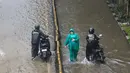 Pengendara dan pejalan kaki melintasi banjir yang menggenangi Jalan Jembatan Tiga Raya, Jakarta Utara, Senin (12/1/2026). Hujan deras yang mengguyur Jakarta menyebabkan banjir di sejumlah wilayah pada Senin (12/1/2026). (merdeka.com/Arie Basuki)