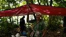 Pemburu madu Malaysia tradisional Zaini Abdul Hamid tersenyum setelah mendirikan tenda untuk mencari sarang lebah di atas pohon raksasa Tualang di hutan Ulu Muda di Sik, Malaysia, (12/3). (AFP Photo/Manan Vatsyayana)