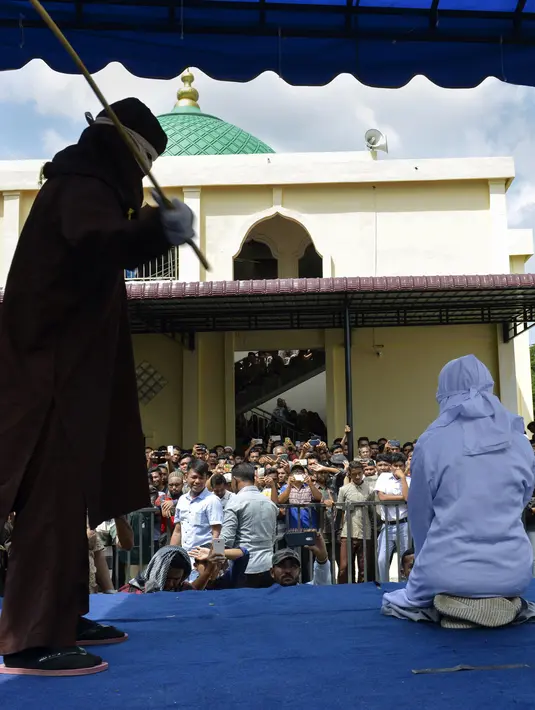 Seorang wanita berusia 19 tahun menjalani hukuman cambuk di depan umum di Banda Aceh (31/1). Dua remaja AS laki-laki (19) dan NS perempuan (19) dicambuk setelah mereka ketahuan berpelukan di depan umum. (AFP Photo/Chaideer Mahyudin)