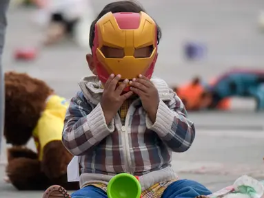 Seorang anak memakai topeng Iron Man saat ikut aksi di Alun-alun Bolivar, Bogota, Kolombia (20/11). Aksi ini memprotes penganiayaan terhadap anak sekaligus meningkatkan kesadaran akan tanggung jawab dalam perlindungan anak. (AFP Photo/Raul Arboleda)