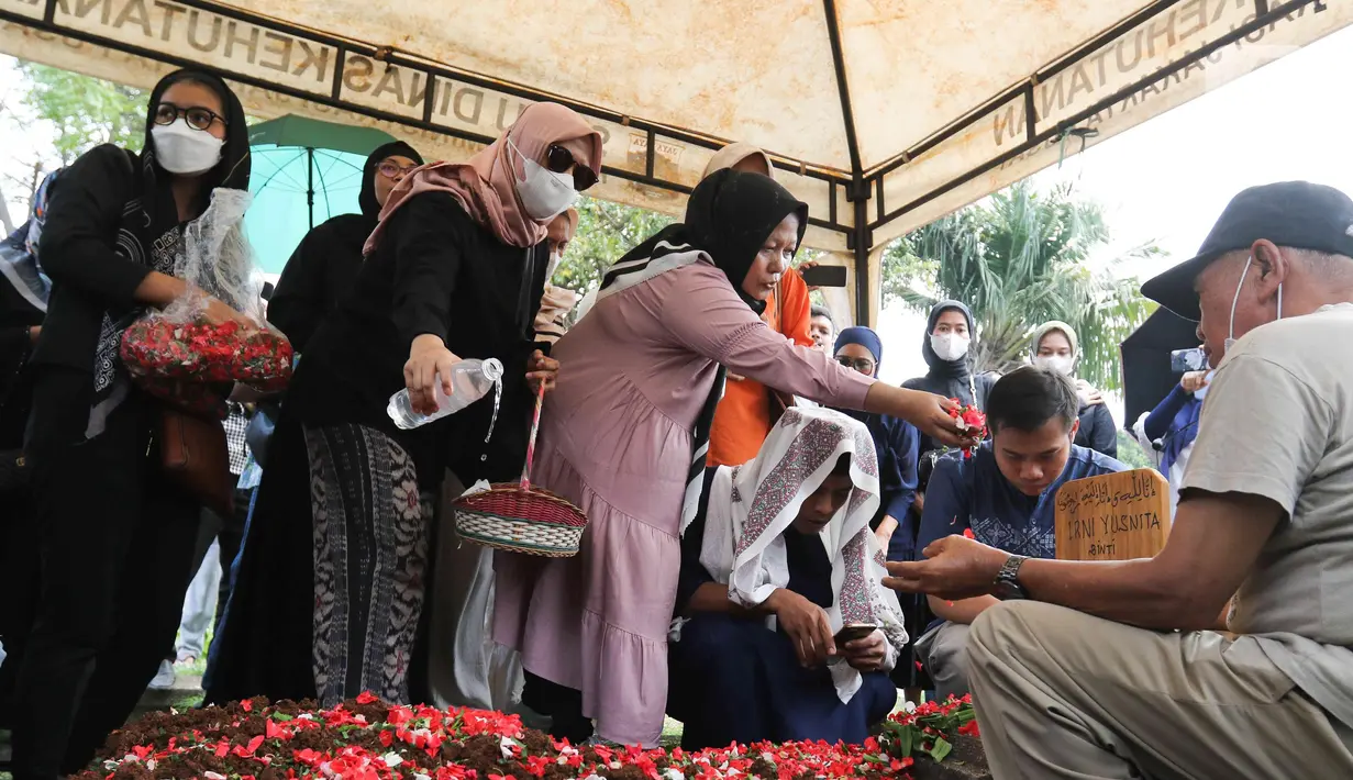 Keluarga dan kerabat menaburkan bunga di makam pelawak Irni Yusnita alias Rini S Bon Bon di TPU Kawi Kawi, Johar Baru, Jakarta, Senin (11/7/2022). Pelawak Rini S Bon Bon  meninggal dunia pada hari Minggu sore (10/7/2022), sebelum berpulang rini sempat mengidap  sakit diabetes. (Liputan6.com/Herman Zakharia)