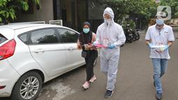 Petugas KPPS menggunakan hazmat sebelum menuju rumah pemilih di kawasan Depok, Rabu (9/12/2020). Petugas jemput bola atau mengambil suara dari warga yang diduga terpapar COVID-19 atau sedang menjalani isolasi mandiri di salah satu perumahan dalam Pilkada Depok 2020. (Liputan6.com/Herman Zakharia)