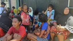 Orang-orang menunggu di luar rumah mereka setelah gempa bumi di Maumere, Indonesia, Selasa (14/12/2021). BMKG menghimbau masyarakat untuk tetap berhati-hati terhadap gempa susulan meskipun status tsunami dengan ancaman waspada telah dicabut. (AP Photo)