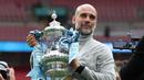 Pelatih Manchester City, Pep Guardiola berfoto dengan Piala FA setelah mengalahkan Chelsea dengan skor 1-0 di partai final di Wembley Stadium hari Sabtu (16/05/2026) malam WIB. (AFP/Adrian Dennis)