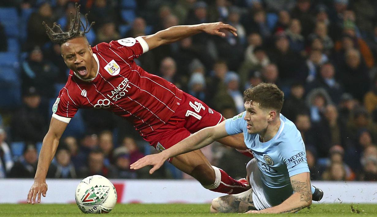 Striker Bristol City, Bobby Reid, terjatuh saat berebut bola dengan bek Manchester City, John Stones, pada leg pertama semifinal Piala Liga Inggris di Stadion Etihad, Selasa (9/1/2018). Manchester City menang 2-1 atas Bristol City. (AP/Dave Thompson)