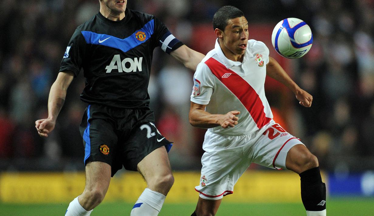 Pemain Southampton, Alex Oxlade-Chamberlain (kanan) berebut dengan pemain Manchester United, John O'Shea pada laga Piala FA di St Mary's Stadium, Southampton, Inggris, 29 Januari 2011. Jersey milik Southampton pada musim 2010/2011 terlihat sangat sederhana. Jersey tersebut didominasi warna putih dengan aksen strip miring berwarna merah. (AFP/Adrian Dennis)