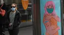 Seorang perempuan melewati tanda grafiti yang mendorong orang untuk divaksinasi di kawasan pusat bisnis Melbourne, Rabu (11/8/2021). Lima juta orang di kota terbesar kedua di Australia tersebut akan tetap berada di bawah perintah tinggal di rumah, setidaknya selama seminggu lagi. (William WEST/AFP)