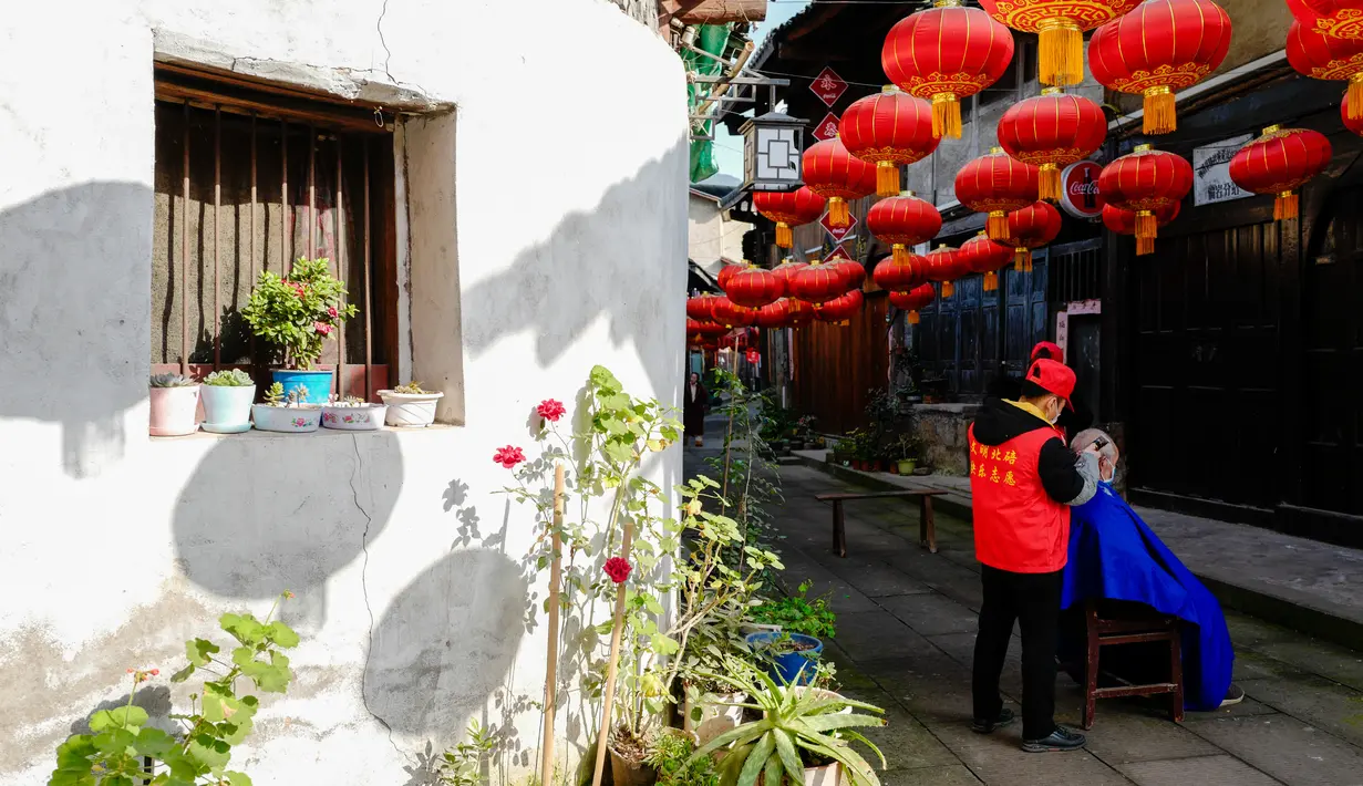 Seorang barber sukarelawan memotong rambut seorang pria di sebuah permukiman di Kota Chongqing, China pada 16 Februari 2020. Sejak merebaknya virus corona COVID-19, sebagian besar tempat potong rambut telah ditutup. (Xinhua/Liu Chan)