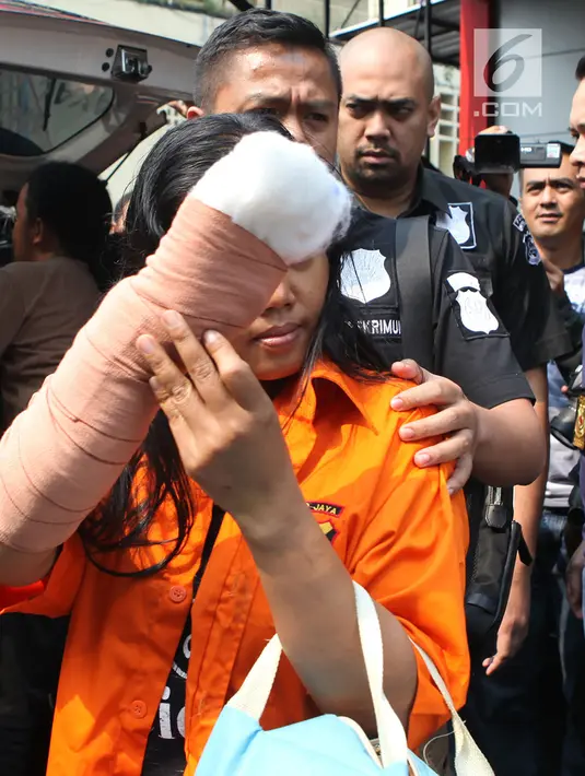 Istri tersangka pembunuhan wartawan Abdullah Fitri Setiawan alias Dufi yang tewas dalam drum, Sari menutupi wajahnya saat digelandang petugas di Polda Metro Jaya, Jakarta, Rabu (21/11). (Merdeka.com/Imam Buhori)