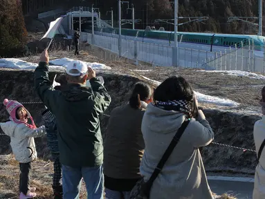 Warga saat menyambut dengan meriah kereta peluru Shinkansen tujuan Shin-hakodate-Hokuto di stasiun Tokyo, Sabtu (26/3). Warga Jepang bersuka cita karena diresmikannya jalur kereta peluru Shinkansen menuju pulau utara Hokkaido. (JIJI PRESS / AFP)