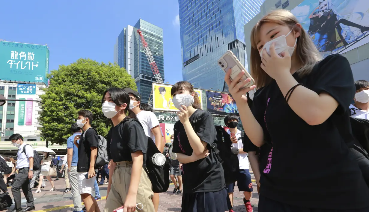 Orang-orang yang memakai masker untuk membantu melindungi diri dari penyebaran virus corona berjalan melintasi persimpangan di Tokyo, Senin (30/8/2021). Per harinya, Jepang bisa mencatatkan lebih dari 20 ribu kasus COVID-19 baru. (AP Photo/Koji Sasahara)