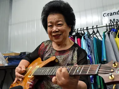 Mary Ho (81) melakukan latihan dengan gitar elektriknya di Singapura, 5 Agustus 2017. Nenek tujuh cucu itu tengah menjadi buah bibir karena akan tampil di hadapan puluhan ribu orang  pada peringatan ke-52 Hari Kemerdekaan Singapura. (Roslan RAHMAN/AFP)