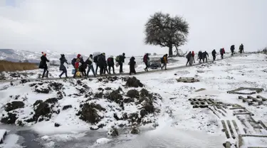 Sejumlah imigran berjalan melewati salju tebal membawa barang-barang mereka melintasi perbatasan Makedonia, dekat desa Miratovac, Serbia, (18/1/2016). (REUTERS/Marko Djurica)