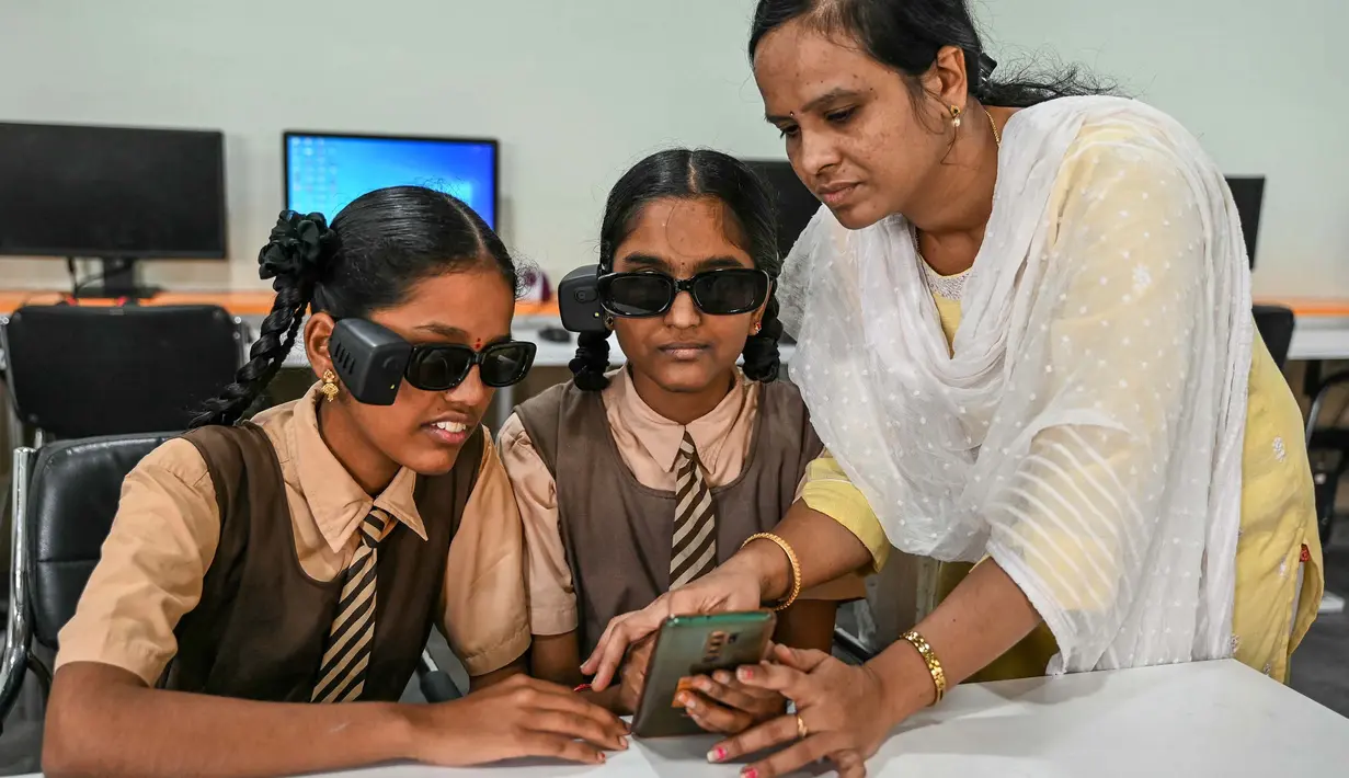 Seorang instruktur membantu para siswa disabilitas netra dalam menggunakan kacamata pintar berteknologi Artificial Intelligence (AI) di sebuah sekolah tunanetra di Hyderabad, India pada Jumat 22 November 2024. (NOAH SEELAM/AFP)