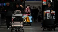 Penumpang mendorong troli barang bawaan saat tiba di Bandara Internasional Beijing pada Senin (20/1/2020). China berada di tengah-tengah kesibukan migrasi manusia tahunan ketika jutaan orang pulang ke kampung halaman mereka untuk menikmati libur Tahun Baru Imlek bersama keluarga. (WANG Zhao/AFP)