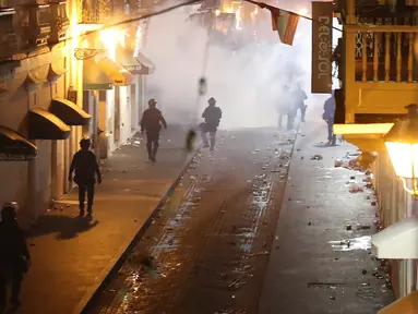 Polisi saat bentrok dengan pengunjuk rasa di Old San Juan, Puerto Rico (22/7/2019). Para pengunjuk rasa menuntut agar Gubernur Ricardo Rossello mundur  dari jabatannya setelah dalam pusaran skandal pesan teks daring tak senonoh dengan para stafnya. (AFP Photo/Joe Raedle)