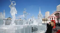Dubes Inggris Katrin Arnold mengambil gambar patung es the Beatles dan Big Ben London di Ulaanbaatar, Mongolia (23/1). Patung dibuat untuk menandai ulang tahun ke-55 pembentukan hubungan diplomatik antara kedua negara. (AFP Photo/Byambasuren Byamba-Ochir)