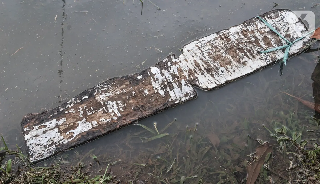 Papan nisan hanyut terbawa banjir di TPU Karet Bivak, Jakarta, Minggu (7/2/2021). Sudin Pertamanan dan Hutan Kota Jakarta Pusat mengungkapkan banjir terjadi akibat lahan tak lagi mampu menampung air hujan serta diperparah dengan lokasi 3 blok makam yang berada di cekungan (merdeka.com/Iqbal Nugroho)