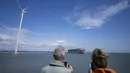 Para wisatawan yang penasaran berkumpul di sebuah jembatan dan tembok laut di pelabuhan Eemshaven saat kapal kargo itu ditarik. Tidak jelas berapa lama waktu yang dibutuhkan untuk menyelamatkan kapal tersebut. (AP Photo/Peter Dejong)