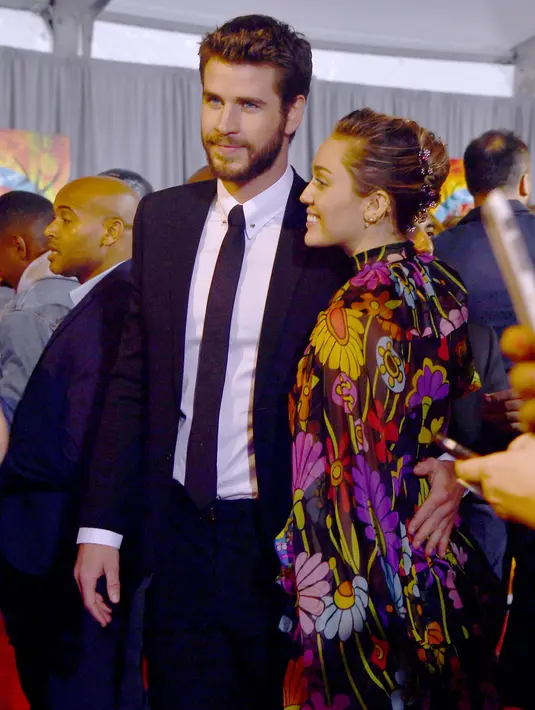 Pasangan selebritis, Miley Cyrus dan Liam Hemsworth menghadiri acara premier film 'Thor: Ragnarok' di California, 10 Oktober 2017. Saat itu, Miley tampil begitu girly dengan mengenakan gaun full color dengan motif bunga-bunga. (Rich Polk/Getty Images/AFP)