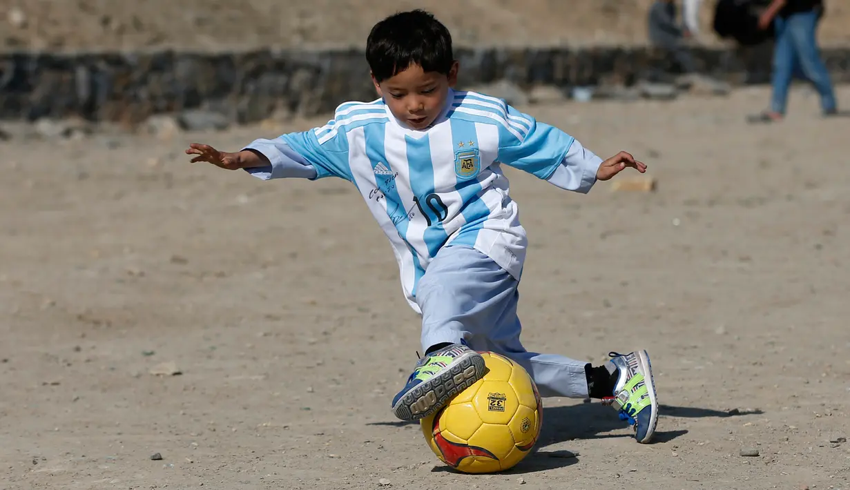 Murtaza Ahmadi (5), bocah asal Afghanistan, memakai jersey yang ditandatangani langsung oleh bintang Barcelona yang juga idolanya, Lionel Messi, ketika bermain sepak bola di sebuah lapangan terbuka di Kabul, Jumat (26/2). (REUTERS/Omar Sobhani)