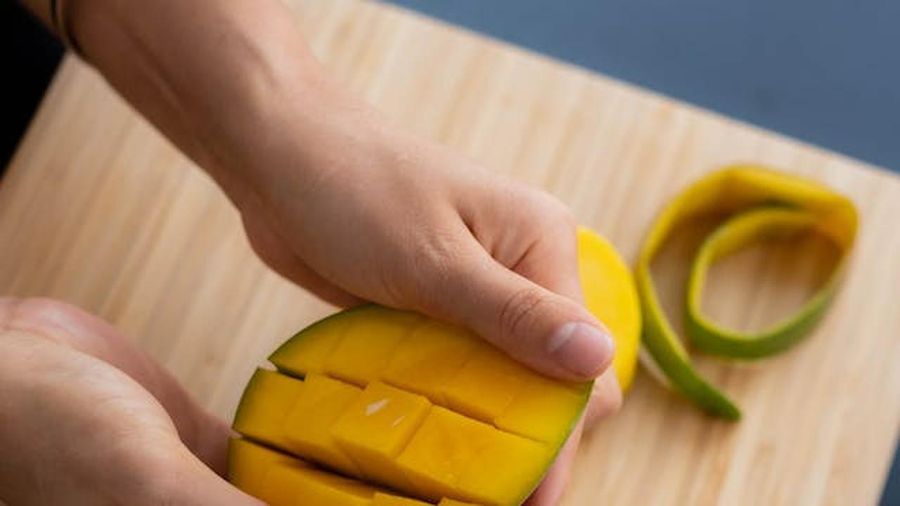 Ilustrasi Seseorang sedang Memegang Buah Mangga yang Sudah Terpotong