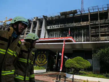 Petugas pemadam kebakaran melintas di depan gedung utama Kejaksaan Agung yang terbakar di Jakarta, Minggu (23/8/2020). Kebakaran yang berawal sejak Sabtu (22/8) malam itu, baru bisa dikuasai pagi ini, Minggu (23/8). (Liputan6.com/Faizal Fanani)
