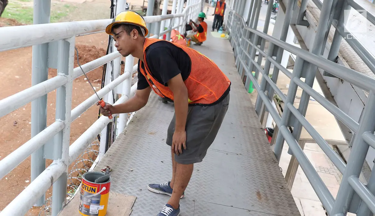 Pekerja mengecat jembatan penyeberangan orang di kawasan Senayan, Jakarta, Jumat (6/7). Pengecatan tersebut merupakan bagian dari proyek revitalisasi JPO guna meningkatnya kenyamanan pejalan kaki. (Liputan6.com/Immanuel Antonius)