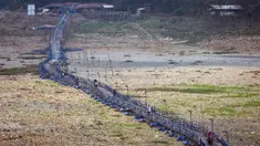 Orang-orang melintas di atas jembatan terapung sepanjang 300 meter yang melintasi Sungai Citarum yang mengering di Cihampelas, Jawa Barat pada 4 Oktober 2023. (Timur MATAHARI/AFP)