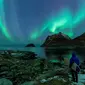 Seorang surfer melihat Cahaya Utara atau aurora borealis di Utakleiv, Norwegia utara (9/3). Cahaya kutub terbentuk dari interaksi medan magnet Bumi dengan lapisan terluar Matahari atau Korona. (AFP/Olivier Morin)