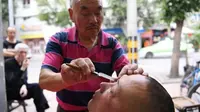 Xiong saat membersihkan mata pelanggannya (shanghaiist.com)