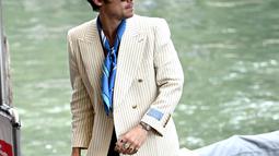 Harry Styles tiba di dermaga Hotel Excelsior selama Venice Film Festival 2022 ke-79 di Venesia, Italia (5/9/2022). Harry yang menandai peran utama pertamanya di film ini, tampak tamapn dalam nuansa gaya tahun 70-an. (AFP/Marco Bertorello)