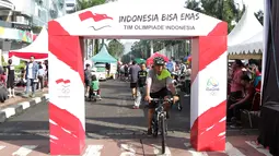 Warga melintas deket gapura kampanye Indonesia Bisa Emas, Road to Rio 2016 di Senayan, Jakarta, Minggu (20/3/2016). (Bola.com/Nicklas Hanoatubun)