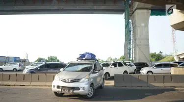 Kendaraan pemudik menerobos pagar pembatas jalan tol di KM 30 Tol Jakarta - Cikampek, kawasan Cikarang, Jawa Barat, Minggu (9/6). Kemacetan yang terjadi di sepanjang jalur tersebut menyebabkan sebagian kendaraan nekat menerobos pagar pembatas untuk berpindah jalur. (Liputan6.com/Immanuel Antonius)