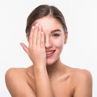 Seorang perempuan dengan rambut digulung tersenyum sambil menutup sebagian wajahnya dengan tangan (Foto Dok: Freepik/diana.grytsku).